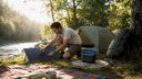 Camper setting up portable solar panel at campsite