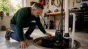 Homeowner inspecting sump pump battery backup system