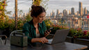 Young woman charging laptop with portable power outdoors