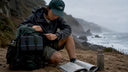 Traveler attaching lightweight power station to backpack outdoors